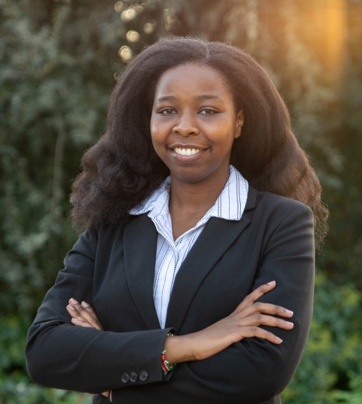 Doreen Joseph stands in business suit with arms crossed smiling at camera.