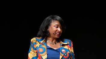 Renetta Garrison Tull seated on stage with a notebook on her lap.