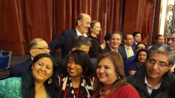 In front of a banquet crowd, a woman takes a selfie of herself, Renetta G. Tull (centered), and another attendee. 