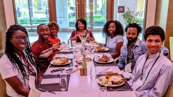 Renetta G. Tull at the head of a table of six student scholars eating a meal together.