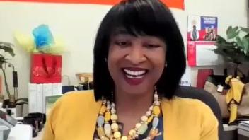 A still from her welcome video features Renetta Tull in her office, wearing a cheerful yellow sweater and beads