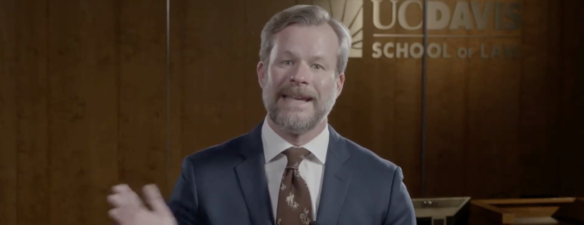 Screenshot of a YouTube video featuring a person in a suit with UC Davis branding in the background.