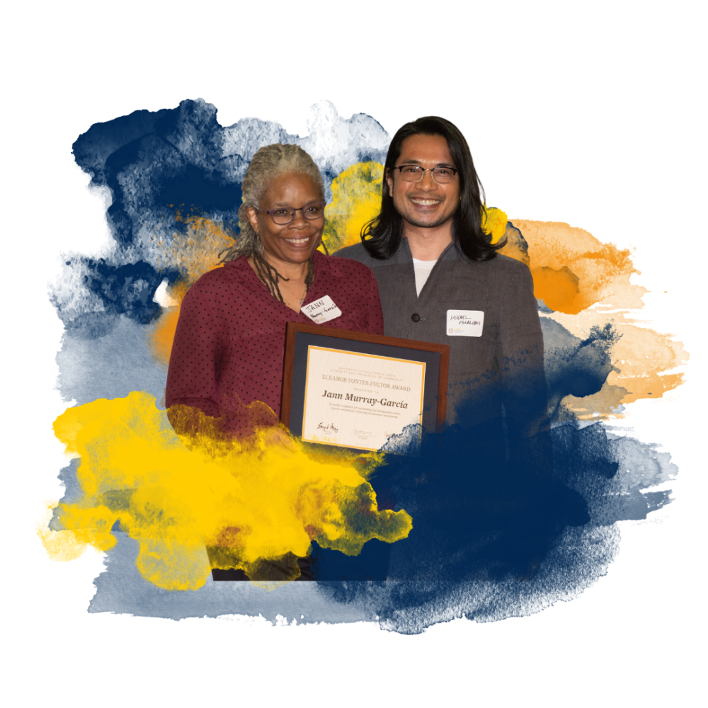 Two people smiling and holding a framed certificate against a colorful abstract background.