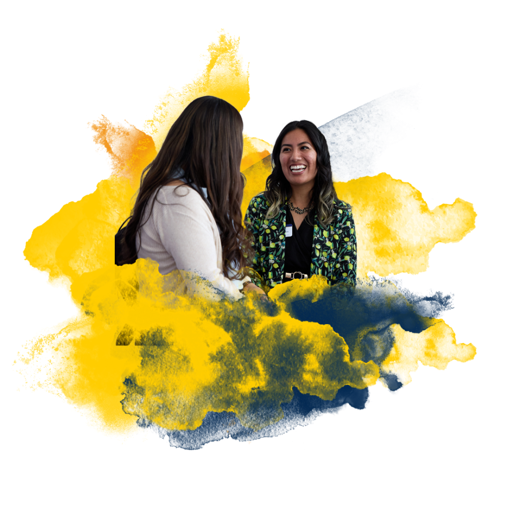 Two women talking with a vibrant yellow and navy blue abstract paint background.