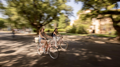 2 students riding on a pathway on campus