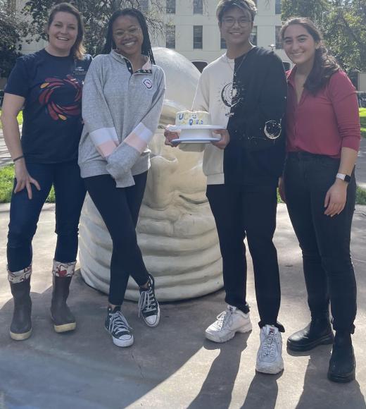 Four people stand next to "Eye on Mrak" Egghead