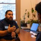 José Roa sits at his desk in the career center talking to a UC Davis student.